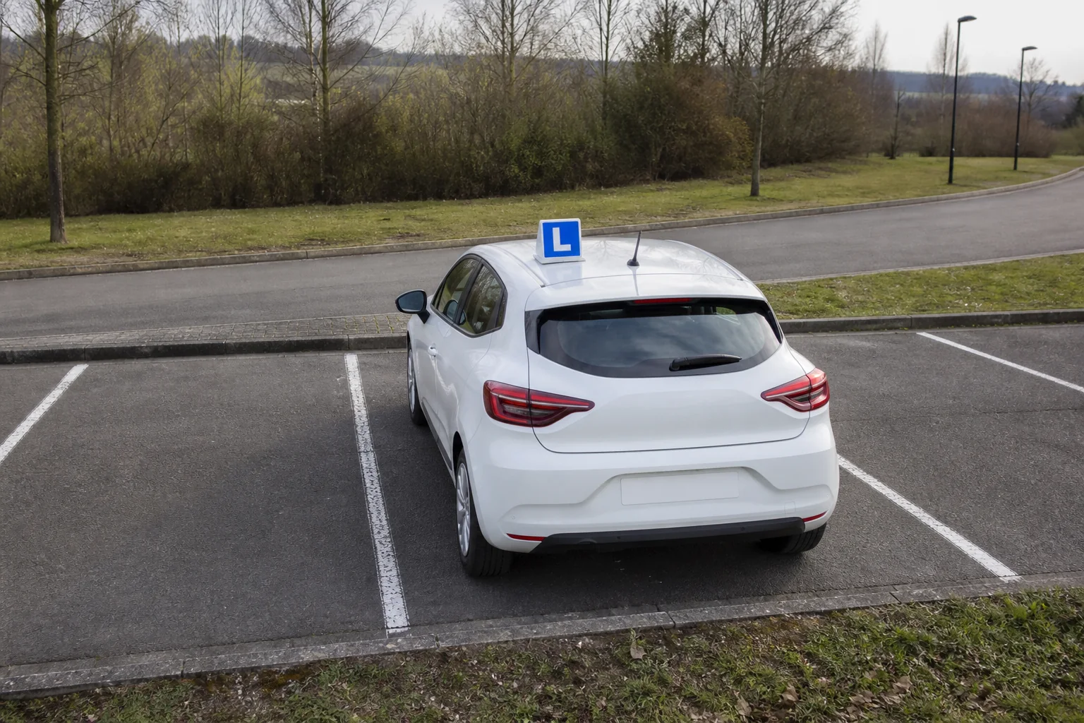 Voiture d'auto-école alignée dans une place de stationnement à Louvain-la-Neuve